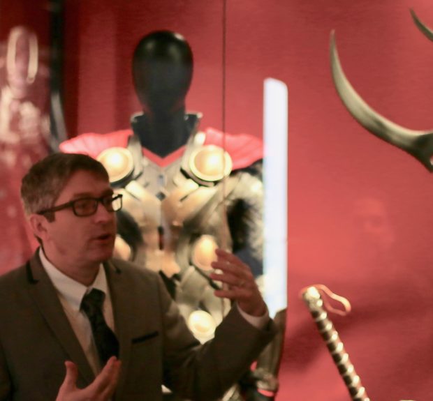 Saunders explains the origins of the exhibition as he stands in front of props from various Thor movies. Photo credit: Alyssa Rasmus/Pink Camera Media.